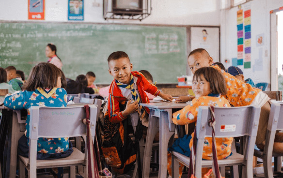 Smiling school children in front of a classroom wall